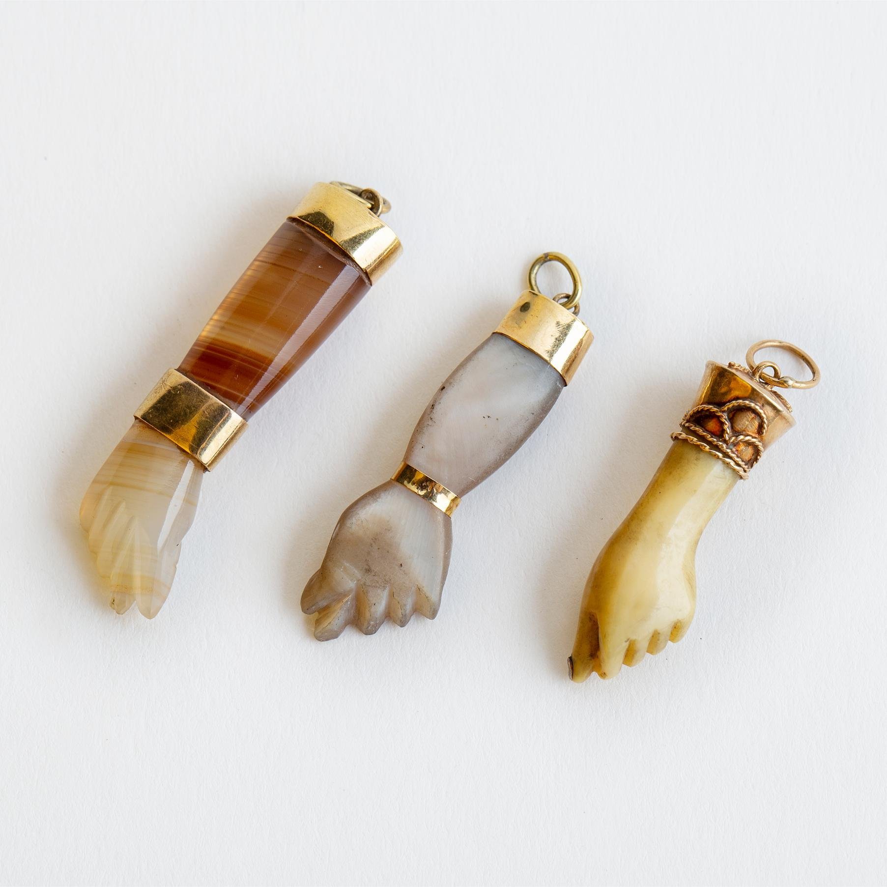 Tres dijes en oro, nácar, ágata y celuloide